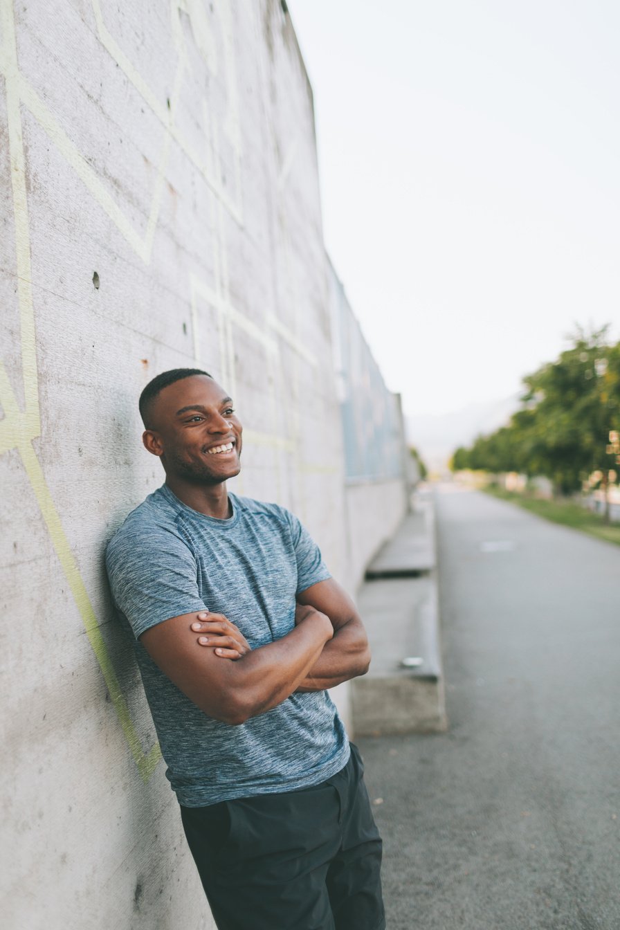 Smiling Man in Sportswear Leaning against the Wall Outdoors